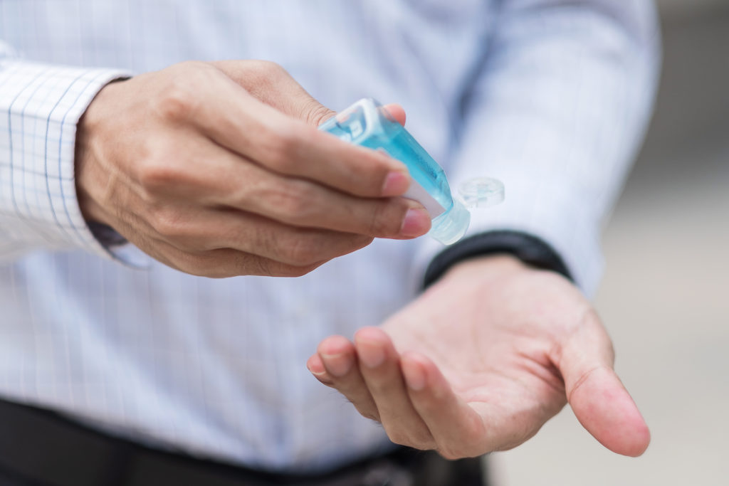 man hands using wash hand sanitizer gel dispenser, against Novel coronavirus or Corona Virus Disease (Covid-19) at public train station. Antiseptic, Hygiene and Healthcare concept