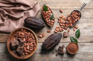 Fave, cabosse e polvere di cacao con su un tavolo di legno