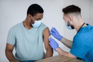 medici vaccino personale sanitario covid coronavirus mascherine ospedale African American male patient getting immunized against covid-19, receiving antiviral vaccine injection at health centre