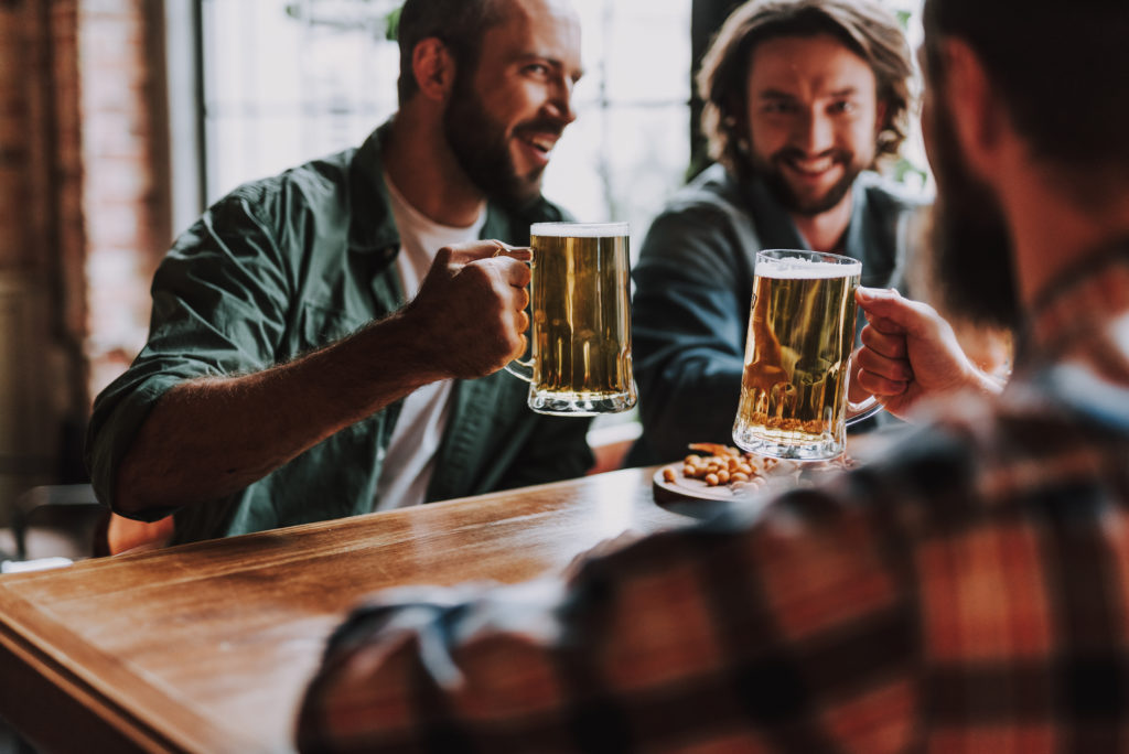 Cheerful friends toasting with drinks while spending time at pub