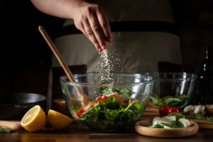 Persona in cucina mette sale su insalta