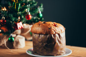 panettone su un piatto con un albero di Natale sullo sfondo; concept: panettoni