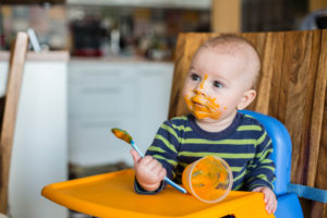Bambino che mangia il purè per la prima volta nella sua vita