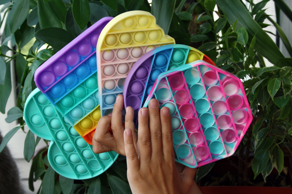 pop-it, mani che tengono pop-it di diverse forme