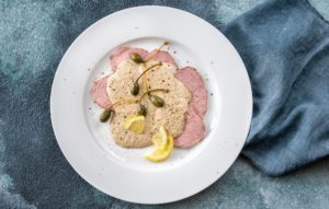 Piatto di vitello tonnato o vitel tonnè con frutti dei capperi (cucunci), fette di limone e pepe