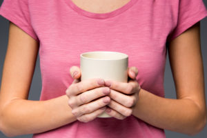 Donna tiene in mano tazza senza manici o bicchiere