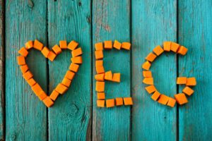 Parola Veg scritta da dolci cubi di zucca luminosi su sfondo turchese vista dall'alto