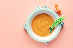 Purè di mele per pappe servite nel piatto su sfondo pastello. Concetto di cibo per bambini. pappa neonati svezzamento frutta