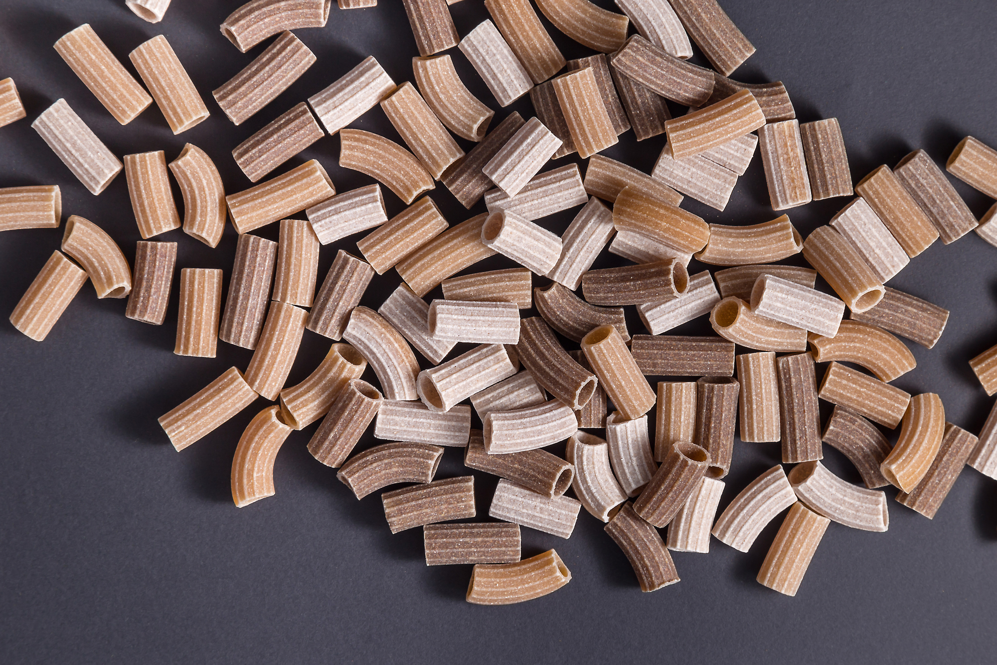 Pasta integrale italiana cruda colorata su sfondo nero pasta biologica biologico