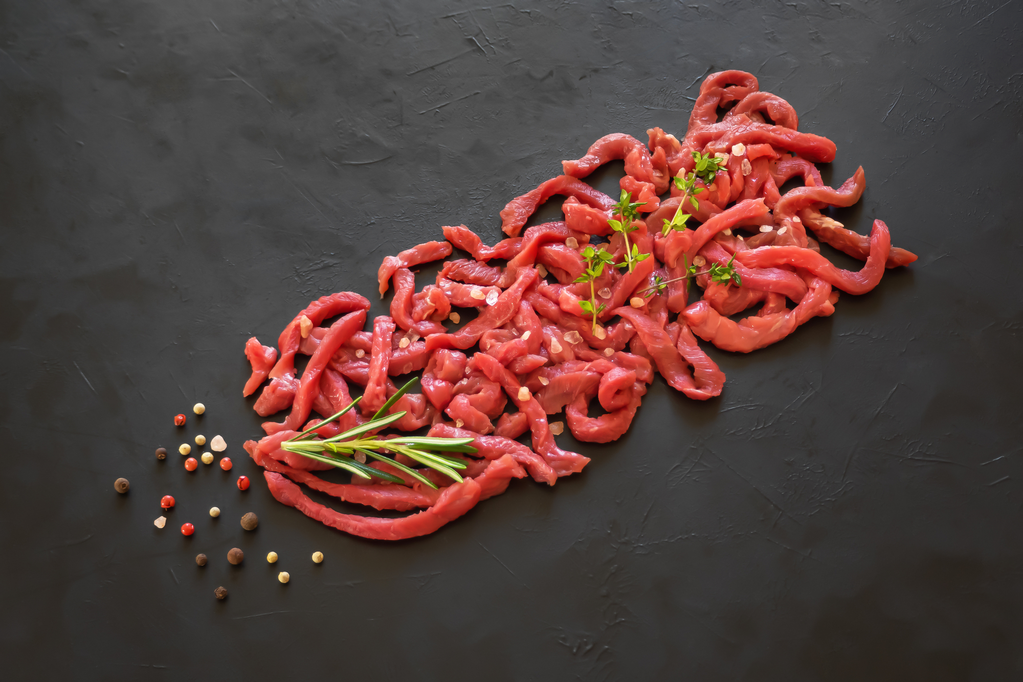 Carne di bovino tagliata a striscioline con pepe, sale e erbe aromatiche