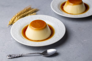 Due creme caramel in piattino con cucchiaino e spighe