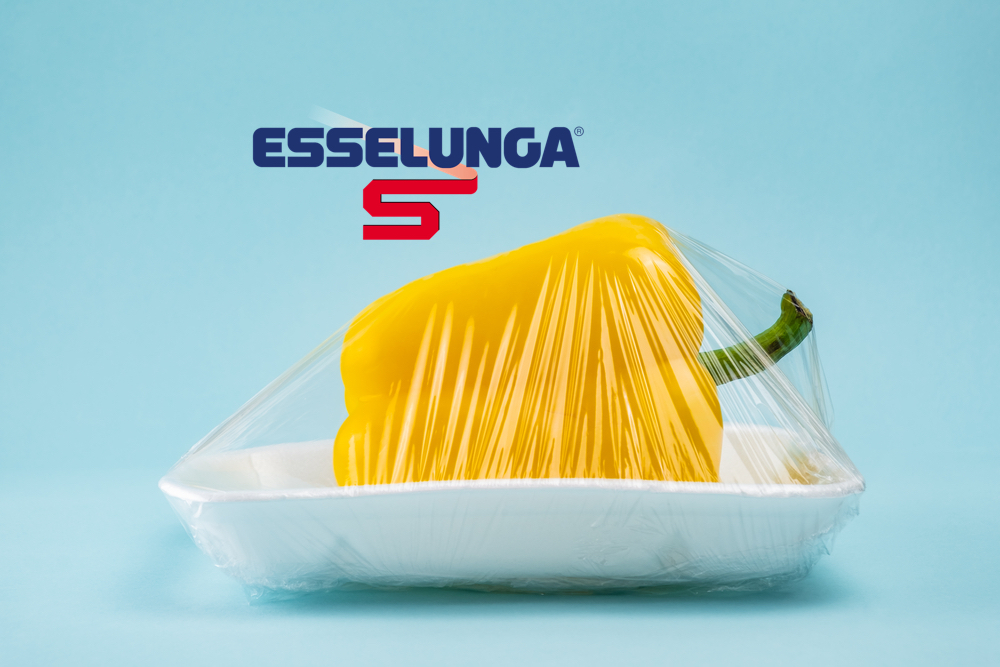 Peperone giallo avvolto in pellicola di plastica su sfondo blu. Concetto di riciclaggio e ambiente: cibo fresco in confezione di plastica esselunga