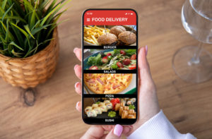Una donna tiene tra le mani uno smartphone con aperta un'app di food delivery