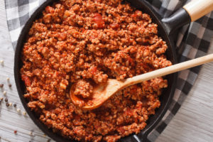 Ragu alla bolognese in una padella con cucchiaio di legno