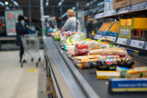 Prodotti sul nastro trasportatore di una cassa di un discount Lidl; accanto prodotti esposti