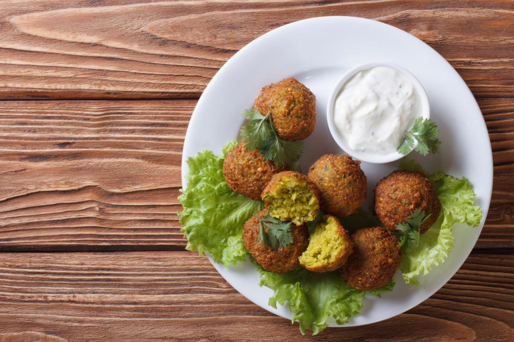 Piatto di falafel di ceci e/o piselli su lattuga con ciotola di salsa tzatziki