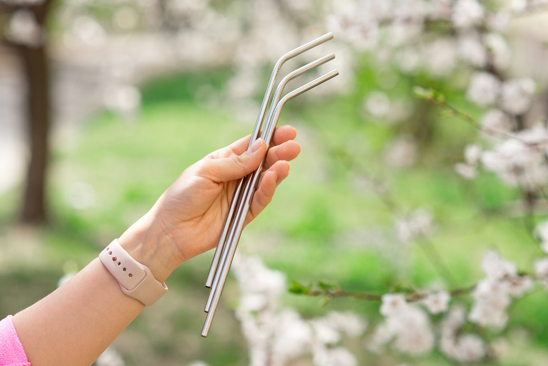 Una ragazza tiene in mano tre cannucce d'acciaio all'aperto
