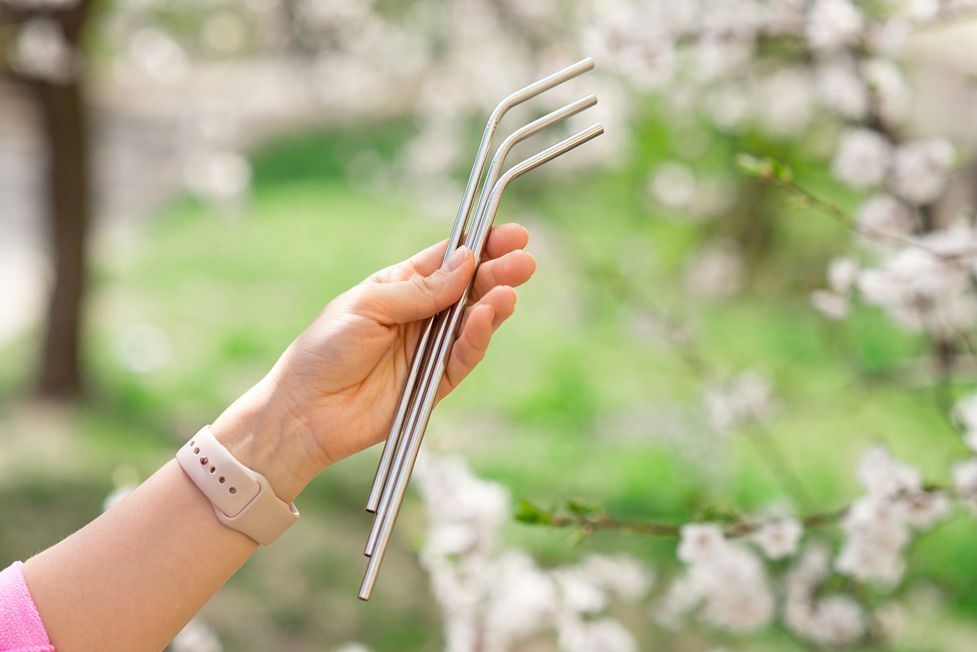 Una ragazza tiene in mano tre cannucce d'acciaio all'aperto