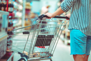 Persona spinge un carrello semivuoto tra le corsie di un supermercato; concept: spesa, prezzi; rapporto Coop