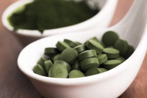 Compresse di Chlorella in una ciotola, accanto a polvere di alga Chlorella; concept: alghe, integratori