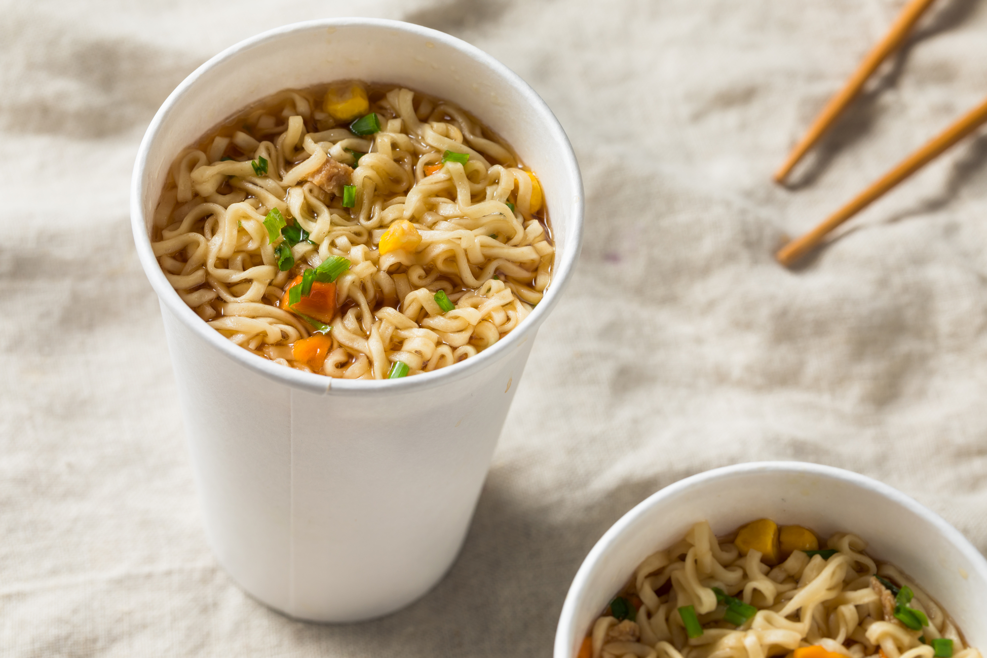 Due tazze di carta con noodles istantanei in brodo; concept: ramen