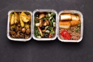 Cibo in contenitori su sfondo nero. Vista dall'alto. Concetto di consegna pfas