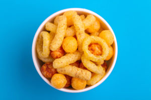 Snack salati misti in una ciotolina; concept: patatine, palline, stick, anelli al formaggio