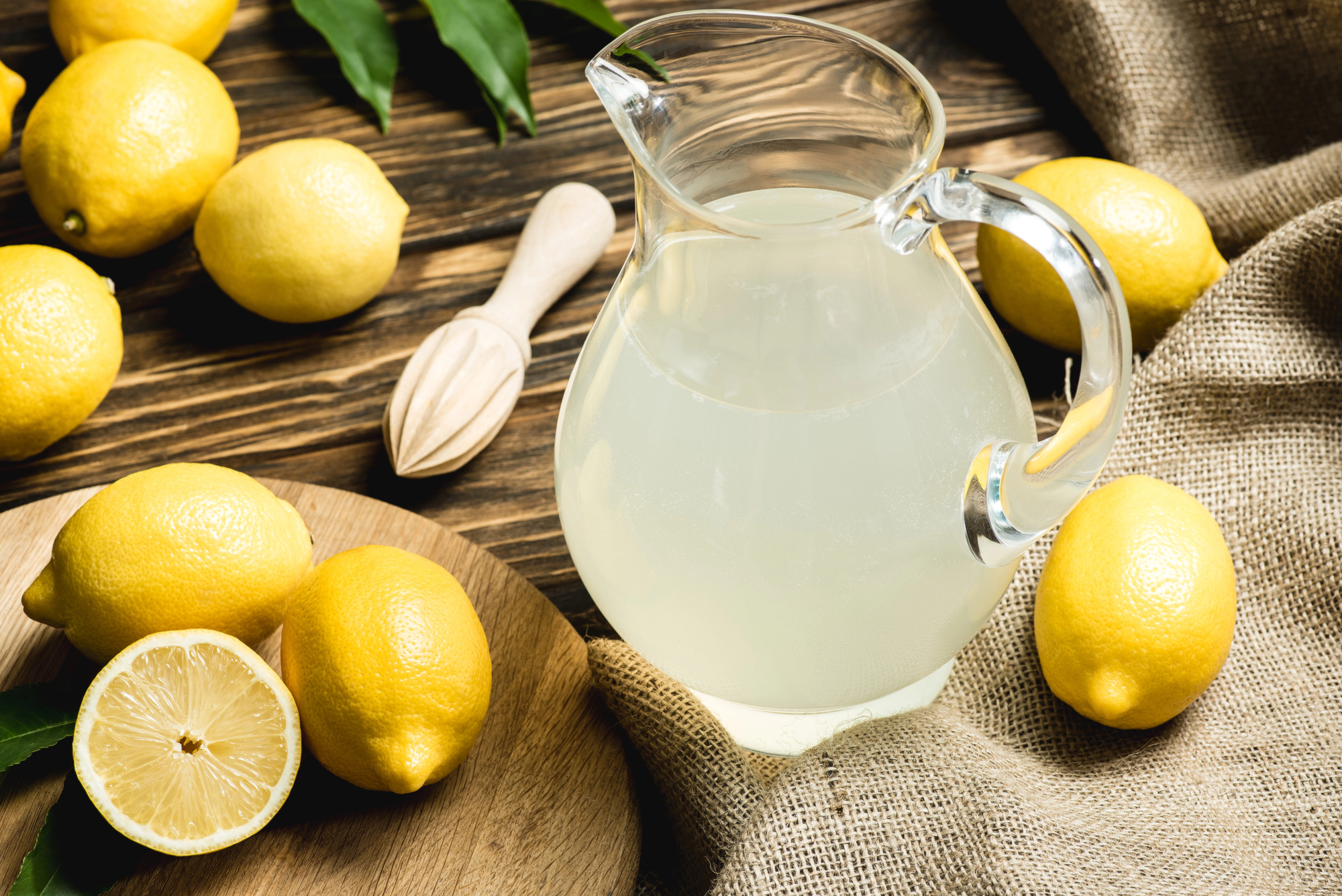 Caraffa di limonata circondata da limoni su un tavolo di legno