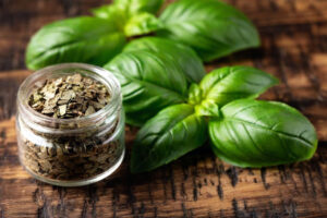 Vasetto di basilico secco, accanto a foglie di basilico fresco su un tavolo