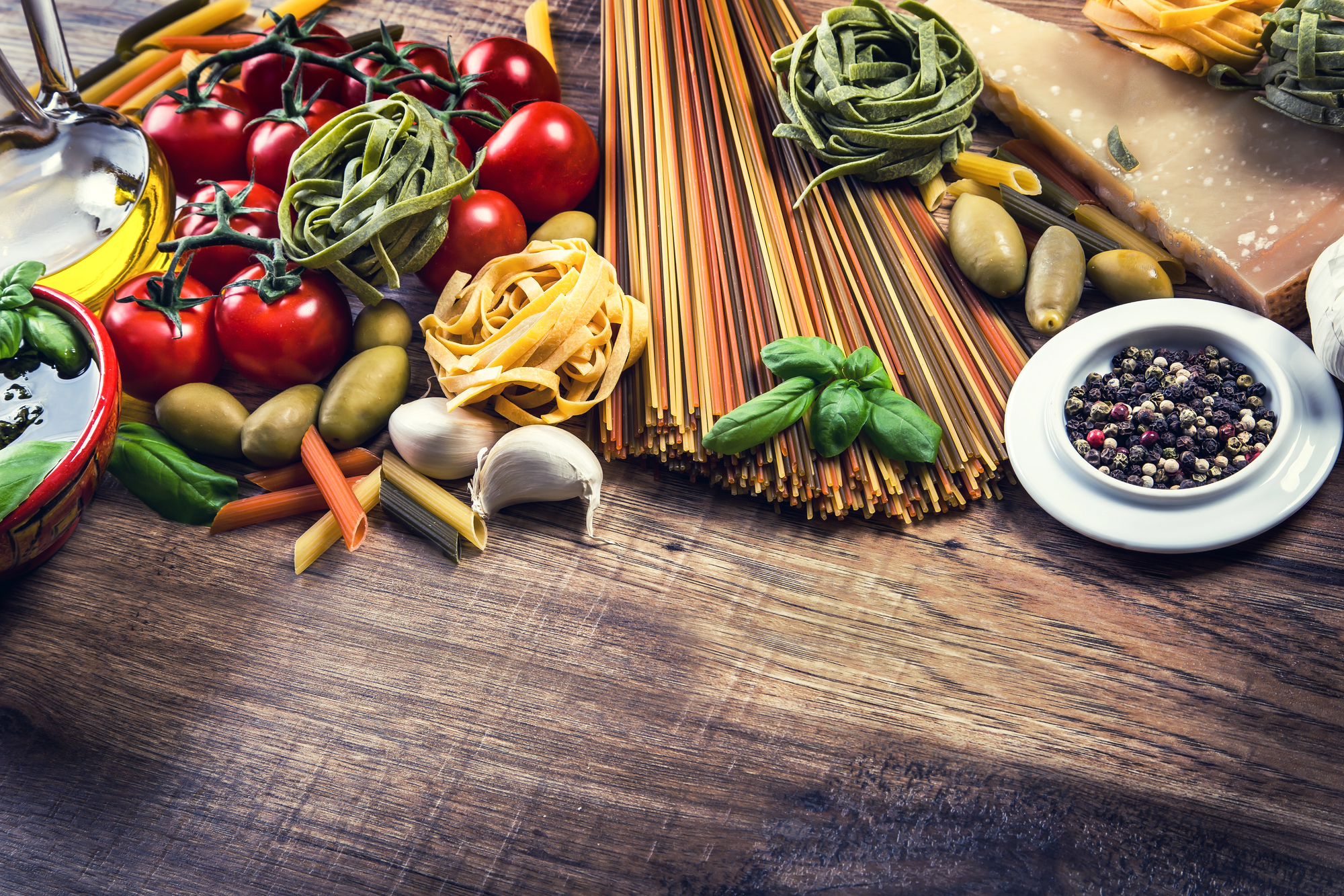 Alimenti tipici della dieta mediterranea e della cucina italiana: pomodori, aglio, olive, pasta, spaghetti e tagliatelle, olio extravergine di oliva, basilico, pepe