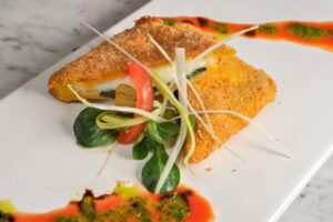 Mozzarella in carrozza tagliata a metà in obliquo su un piatto rettangolare con erbe decorative