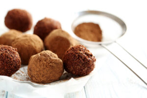 Tartufi dolci di cioccolato accanto a un setaccio con cacao amaro in polvere