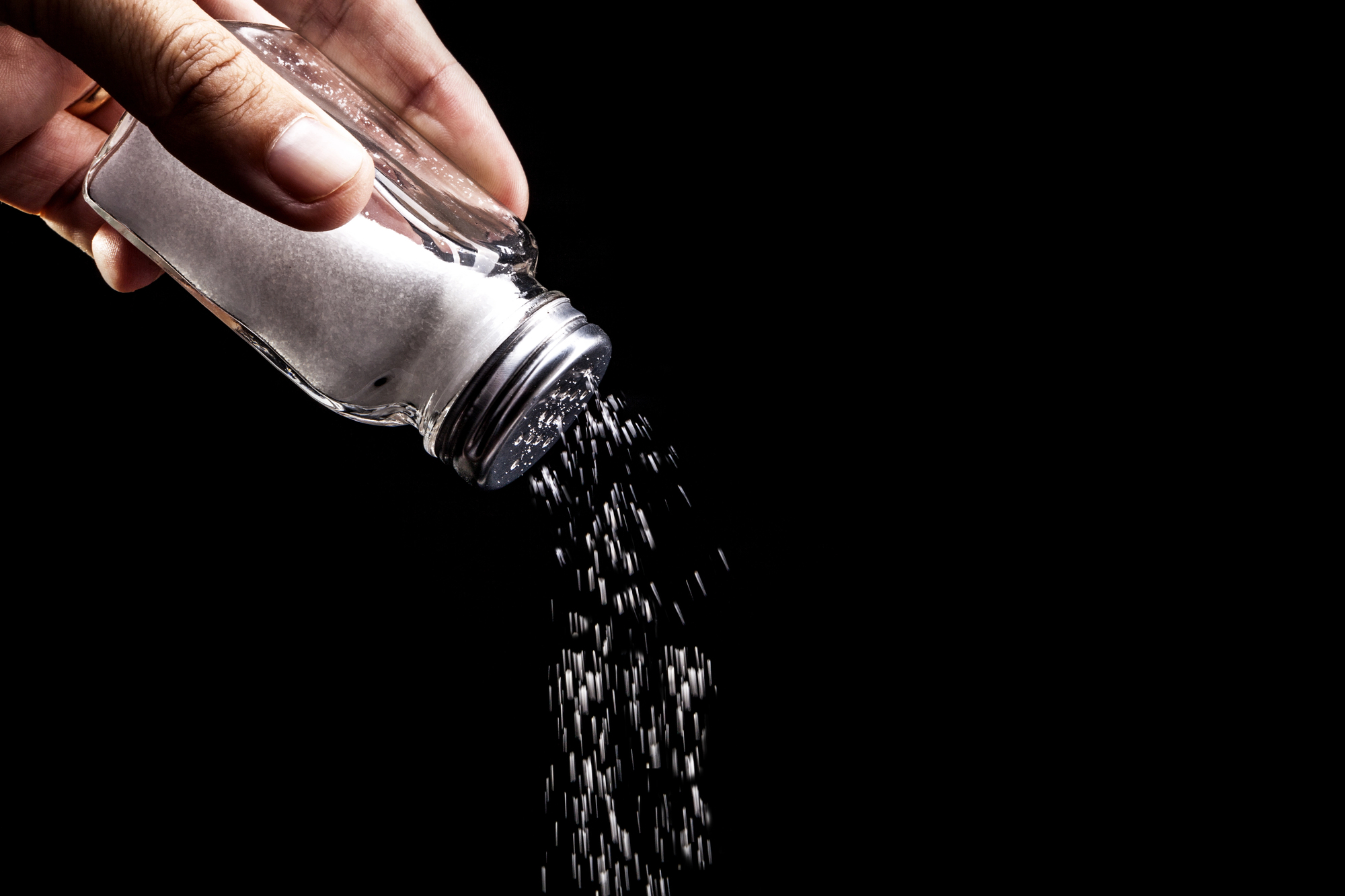 Sale versato da una saliera su sfondo nero