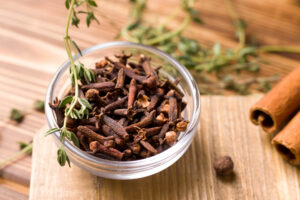 Ciotolina di chiodi di garofano, attorno erbe aromatiche e cannella; concept: spezie