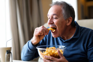 persona uomo mangiare snack patatine junk food Depositphotos_843477510_XL